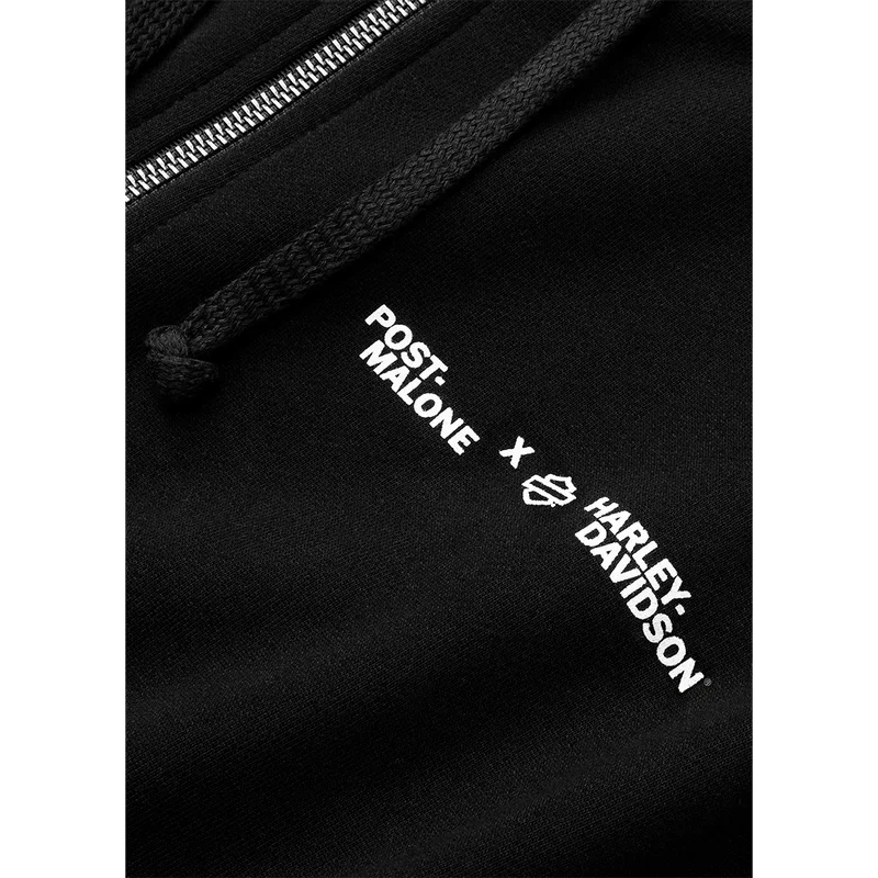 Close-up detail of Post Malone x Harley-Davidson collaboration logo printed on the chest of the black zip hoodie